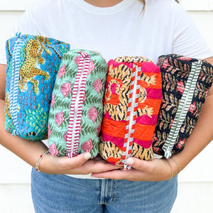 Person holding four colorful quilted items with various patterns